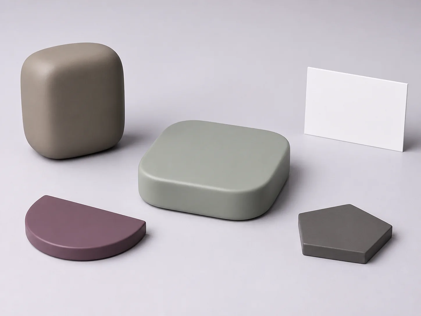 Illustrative UHMW request-planning layout with one unmarked muted mineral ochre-grey opaque compact upright box-superellipsoid with one gently flattened edgeless upper surface, one integral flat underside and one continuous broadly curved closed exterior and one separate unmarked dusty-plum opaque low flat-sided half-oval-footprint solid beside one monolithic pale sage-grey opaque low rounded-square-footprint solid with one broad unmarked flat rounded-quadrilateral top face, one continuous plain outward-convex side surface, a fully closed envelope and no opening, one fully separate unmarked warm-graphite opaque low pentagonal witness coupon without an indentation or other mark, and one completely blank upright matte-white landscape-proportion card