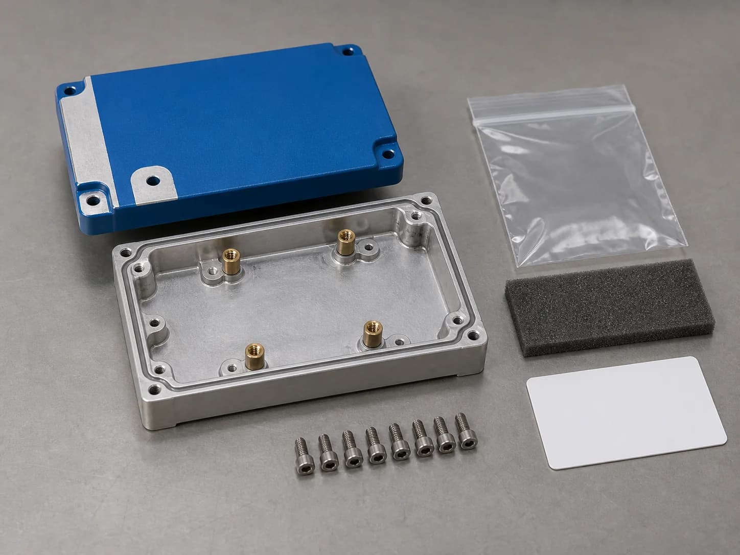 Illustrative finishing-and-assembly planning layout with a blue-coated aluminum enclosure showing protected bare contact pads and edge references, installed standoffs beneath an offset cover, and a clear protective pouch beside an unlabeled inspection card