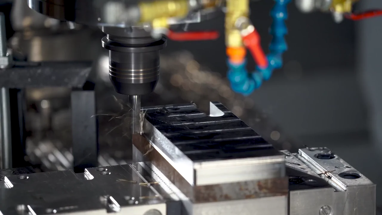 A milling cutter working a metal component, photographed during CNC machining