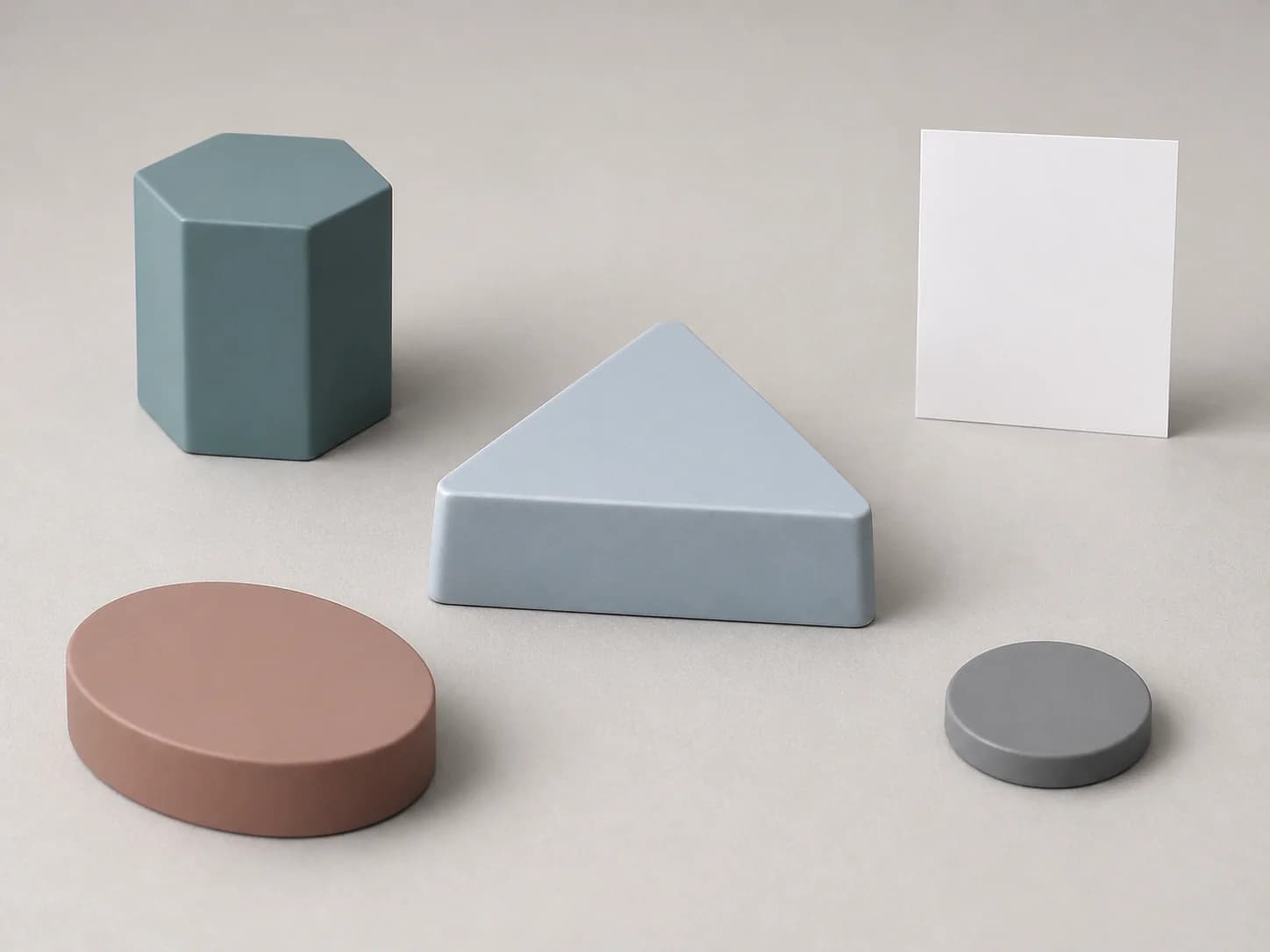 Illustrative Plastic request-planning layout with one unmarked muted blue-green opaque short upright hexagonal form and one separate unmarked muted clay opaque low oval form beside one monolithic pale blue-grey opaque low truncated triangular generic solid with one broad unmarked triangular top face, plain outward-sloping side faces, a fully closed envelope, blunt nonfunctional edges and no opening, one fully separate unmarked mid-grey opaque low circular witness coupon without an indentation or other mark, and one completely blank upright matte-white card
