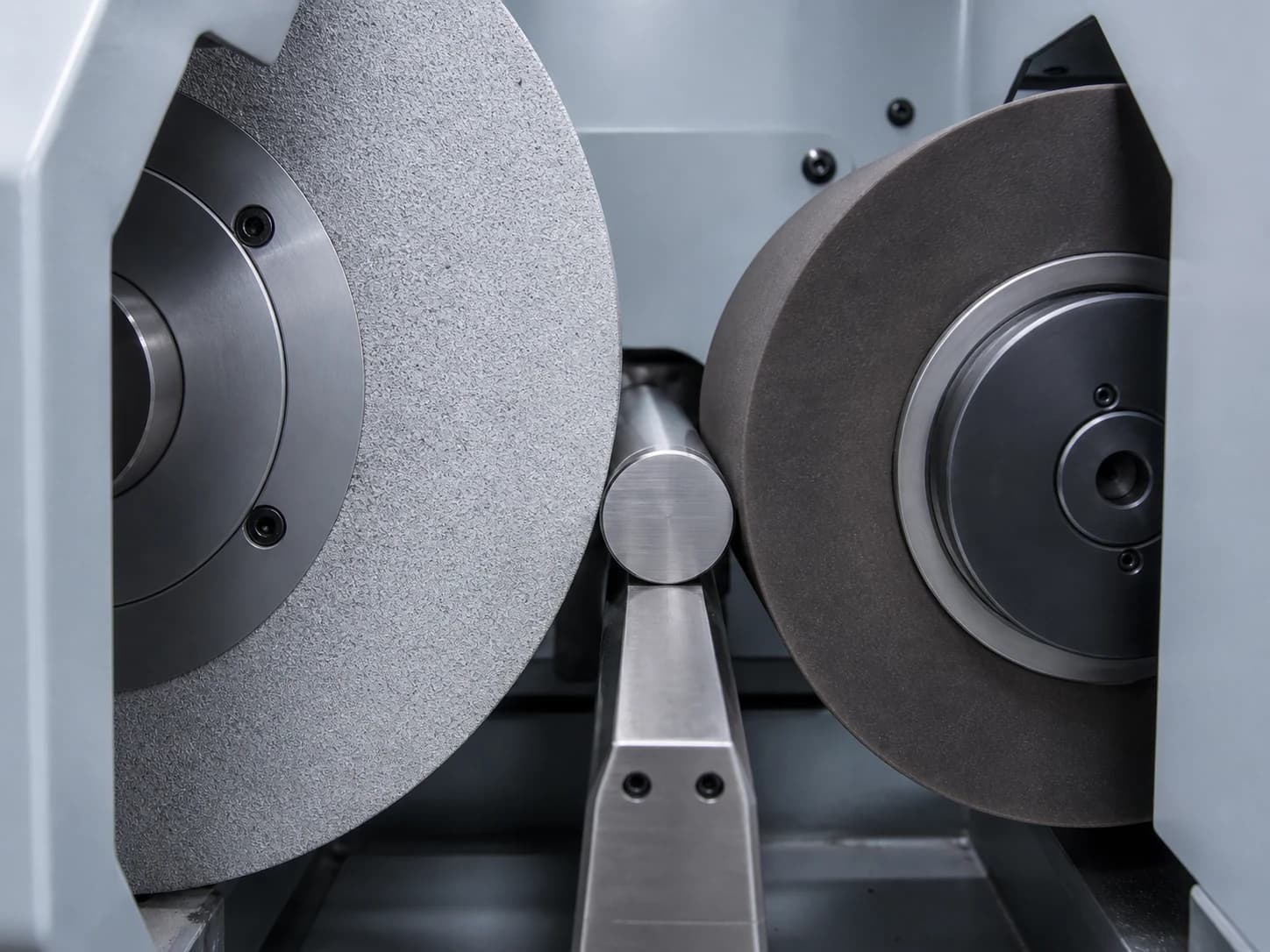 Illustrative centerless grinding setup showing a cylindrical workpiece supported between a grinding wheel, regulating wheel, and work-rest blade